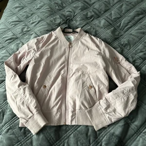 Beige bomberjacka från Bershka - Rosa bomberjacka från Bershka. Jackan har en dragkedja framtill och två fickor med knappar. Perfekt för vår och sommar ! Den är i bra skick, färgen är som på bilden med etikett på. 