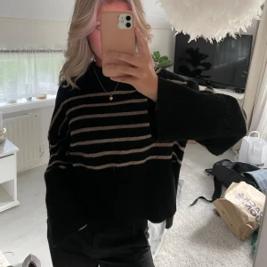 Svart och beige randig tröja - Säljer en supermysig svart tröja med beige ränder. Tröjan är i nyskick och passar perfekt till både vardag och fest. Den är gjord av ett mjukt material som känns skönt mot huden.