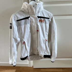 Helly Hansen regnjacka - Helly Hansen regnjacka i väldigt bra skick med infällbara luva.  sparsamt använd men säljes  pga. Blivit något för liten för mig. 