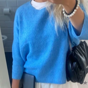Blå stickad tröja - Säljer en superfin blå stickad tröja som är perfekt för kyligare dagar. Den har en normal passform och trekvartsärmar, vilket gör den både bekväm och stilren. Perfekt att matcha med jeans eller en kjol för en avslappnad look.
