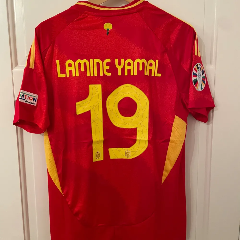 Säljer en fotbollströja från Spanien med Lamine Yamal #19 på ryggen. Tröjan är en reprint. Storlek: M. Ansvarar ej för postens slarv. Endast handtvätt gäller, gnugga ej på blöta prints.. Sportswear.