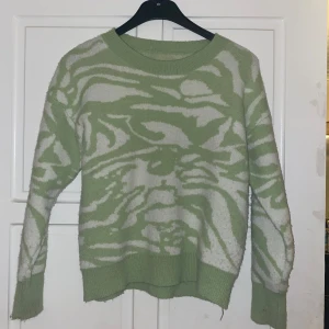 Grön och vit mönstrad tröja - Säljer en cool grön och vit tröja med ett unikt mönster. Den är perfekt för både höst och vår med sina långa ärmar och mjuka material. Tröjan har en avslappnad passform och ribbade kanter vid ärmslut och nederkant. 