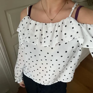 Vit offshoulder blus med prickar - Säljer en söt vit offshoulder blus med svarta prickar och volangdetalj, från Gina Tricot i storlek 34🤍