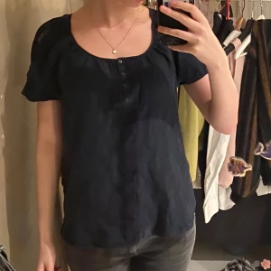 Mörkblå blus med knappar - Säljer en mörkblå blus med korta ärmar och knappar framtill. Jättegullig men inte min vardagliga stil🫶
