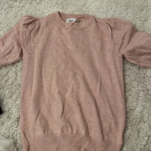 Rosa tröja från Saint Tropez - Säljer en söt rosa tröja från Saint Tropez i storlek XS. Tröjan har puffiga ärmar och ribbade kanter vid hals och nederkant. Perfekt för en stilren look!