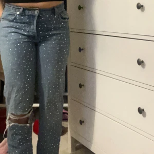 Blå jeans med strassdetaljer - Unika raka/ mom jeans med glitter på, endast använda fåtal gånger. Perfekta till en stilren t shirt eller för att göra din outfit lite roligare! 