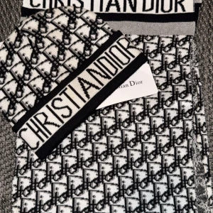 Mössa och halsduk från Christian Dior - Snygg mössa och halsduk från Christian Dior i svart och vit med ett ikoniskt mönster. Mössan och halsduken har en bred kant med logotypen 'Christian Dior' i svart text. Perfekt för att hålla stilen under kallare dagar.