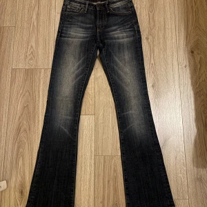 Lågmidjade bootcut jeans från Crocker - Snygga mörkblå lågmidjade bootcut jeans från Crocker med klassisk femficksdesign och knappgylf. Perfekta för en avslappnad stil med en touch av vintagekänsla.