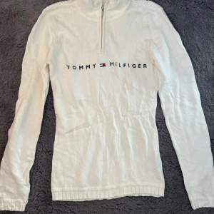 Säljer en snygg vit polotröja från Tommy Hilfiger i mycket bra skick. Tröjan har en halv dragkedja och det klassiska Tommy Hilfiger-loggan broderad på bröstet.