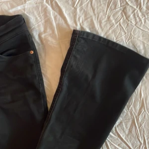 Svarta bootcut jeans - Säljer ett par svarta bootcut jeans från Gina tricot i storlek 32. De har en klassisk femficksdesign med knapp och dragkedja framtill. Perfekta för både vardag och fest! 💗