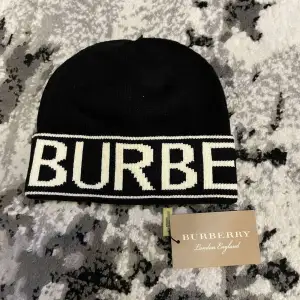 Snygg svart mössa från Burberry med vit text på uppviket. Perfekt för att hålla sig varm och stilren under kyliga dagar. Passar både till vardags och lite finare tillfällen. Utan pris lapp.