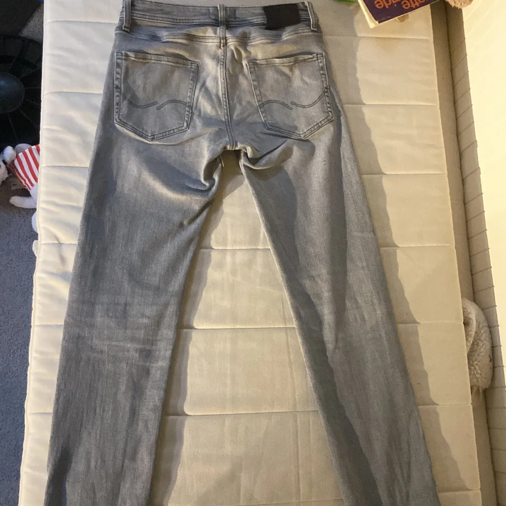 Säljer ett par snygga grå jeans från Jack & Jones. De har en klassisk femficksdesign och är i väldigt bra skick. Perfekta för både vardag och fest! Passformen är straight och de har en knappgylf. Bälte ingår för 100kr extra.. Farkut & Housut.