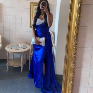 Blå balklänning med pärldetaljer - Säljer min fantastiska designade blå balklänning med en glittrig pärlbeströdd överdel. Klänningen har en elegant slits och är perfekt för bal eller fest. Materialet är glänsande och ger en lyxig känsla. Passar perfekt för en speciell kväll! Är bara använd 1 gång, i perfekt skick. Passar både personer som har stl 34/36, hör av er för önskan om fler bilder 💕💕💕💕kan alltid diskutera pris jag designa den för 4500kr säljer nu för 2500kr