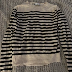Randig tröja från ZARA - Säljer en snygg randig tröja från ZARA i svart och beige. Den är perfekt för både höst och vår med sina långa ärmar och mjuka material. Tröjan har en klassisk stil som passar till det mesta. Perfekt för en casual look eller att klä upp med accessoarer