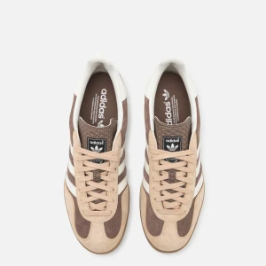 Adidas Gazelle i bruna och beige toner - Bara använda en gång. Säljes pågrund av fel storlek! Säljer ett par klassiska Adidas Gazelle sneakers i bruna och beige toner med vita detaljer. Skorna har snörning och den ikoniska tre-randiga designen på sidorna. Perfekta för en avslappnad stil.