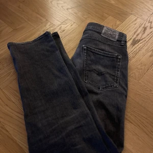 Mörkgrå Replayjeans  - Snygga mörkgråa jeans från Replay med klassisk femficksdesign och knappgylf i storlek 14A. Perfekta för en avslappnad stil. Märkeslogga på bakfickan och bältesslingor för extra stilpoäng. Tveka inte på att höra av er om ni har några som helst funderingar. Pris kan diskuteras 