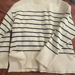 Vit och svart randig tröja från Zara - Säljer en stilren vit tröja med svarta ränder från Zara. Tröjan har långa ärmar och en ribbad krage samt nederkant. Perfekt för en avslappnad look.