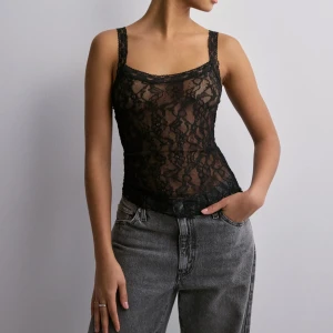 Svart spetslinne - Snyggt svart spetslinne med smala axelband och transparent design. Perfekt för en trendig look. Lappen kvar!