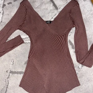 Brun ribbad topp - Säljer en snygg brun ribbad topp med v-ringad design. Skönt material på den.