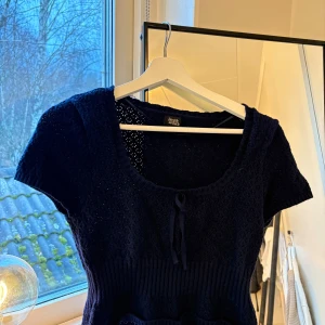 Marinblå topp från Beverly and Beck - Säljer en barinblå topp från Beverly and Beck i storlek M. Toppen har korta ärmar och en söt knytdetalj framtill. Materialet är stickat med ett fint mönster!använd 1 gång