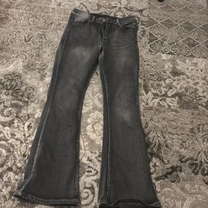 Grå bootcut jeans - Snygga grå bootcut jeans med klassisk femficksdesign. Perfekta för en avslappnad stil med en touch av retro. De har en knapp och dragkedja framtill.