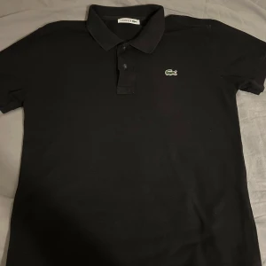 Svart pikétröja från Lacoste - Säljer en klassisk svart pikétröja från Lacoste i storlek S.