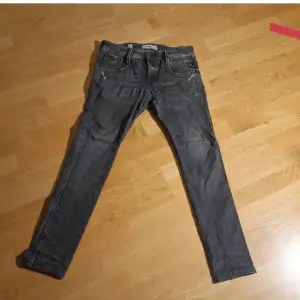 Säljer ett par grå Replay jeans i bra skick. De har en snygg sliten look med detaljerade slitningar vid fickorna. Perfekta för en casual stil och passar till de flesta tillfällen. Märket Replay syns tydligt på fickan och bak i midjan.