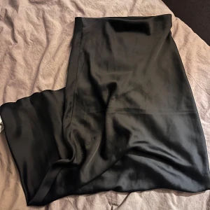 Svart sidenkjol - Betalas via swish! Säljer en elegant svart sidenkjol i mycket bra skick. Kjolen har en slät och glansig yta som ger en lyxig känsla. Perfekt för festliga tillfällen eller en stilren vardagslook. Passar bra till både höst och vinter. Storlek är