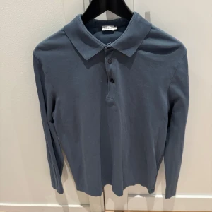 Blå pikétröja från Filippa K - Säljer en stilren blå pikétröja från Filippa K i storlek M. Tröjan har långa ärmar och en klassisk krage med knappar framtill. Perfekt för både vardag och lite finare tillfällen. Skön och enkel att matcha med det mesta! 💙