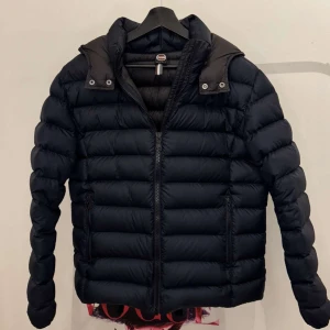 Mörkblå vinterjacka från Colmar - Säljer en stilren svart dunjacka från Colmar. Jackan har en dragkedja framtill och långa ärmar. Perfekt för kyligare dagar med sin quiltade design som håller värmen. 