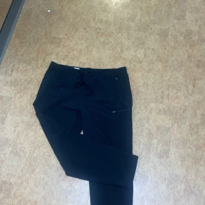 Svarta mjukisbyxor med dragkedja - Säljer ett par svarta mjukisbyxor i mycket bra skick. De har en bekväm passform med snörning i midjan och praktiska dragkedjor på fickorna. Perfekta för en avslappnad dag hemma eller en promenad i parken. Passar till alla säsonger! byxan kostar egentligen 1000 kr. Priset kan diskuteras