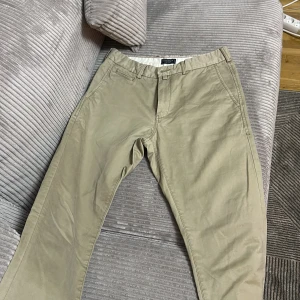 Beige chinos  - Säljer ett par snygga beige chinos i bra skick. De har en normal passform och är perfekta för både vardag och lite mer uppklädda tillfällen. Byxorna har knappar bak och bälteshällor för extra stil. Perfekta för vår och sommar!