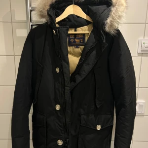 Svart parkajacka från Woolrich - Säljer en svart parkajacka från Woolrich i mycket bra skick. Jackan är köpt på Care of Carl och därmed äkta! Sitter som M. Perfekt inför vintern!