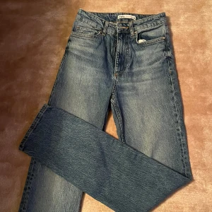 Blå jeans från Zara - Säljer ett par klassiska blå jeans från Zara i storlek 34. De har en snygg vintage-look med fem fickor och knappgylf. Perfekta för både vardag och fest!🩷pris kan diskuteras!