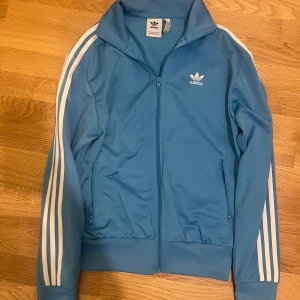 Adidas fleecejacka  - Säljer denna snygga ljusblå zipup tröjan från Adidas. Den är i jättebra skick. Strl s (herrstorlek) så den är mer baggy.