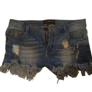 Blå jeansshorts från Almost Famous - Säljer ett par coola blå jeansshorts från Almost Famous. De har en snygg slitning och fransar längst ner .