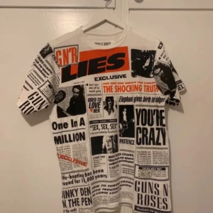 Vit t-shirt med Guns N' Roses-tryck från Pull&Bear - Säljer en cool vit t-shirt från Pull&Bear med ett unikt Guns N' Roses-tryck. T-shirten har korta ärmar och är perfekt för alla rockälskare. Den är i bomull och har en normal passform. Perfekt för sommarens festivaler eller vardagsbruk. 🎸