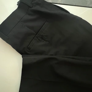 Svarta kostymbyxor  - Svarta kostymbyxor med mellanhög midja. Har fickor