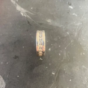 Silverring med stenar - Säljer en elegant äkta silverring med infällda stenar runt om. Ringen har en stilren design som passar perfekt till både vardag och fest. Den är i bra skick och ger en lyxig känsla. Perfekt för dig som vill ha något glittrigt och stilrent på fingret!