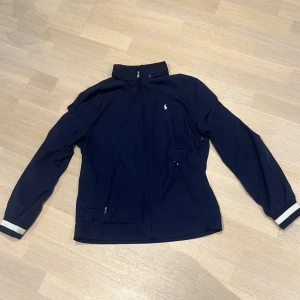 Ralph lauren jacka - Ralph lauren vindjacka. Funkar perfekt på våren och hösten. 10/10 skick. Använt ett fåtal gånger förra våren men har växt ut den. 18-20 vilket motsvarar s/xs. 