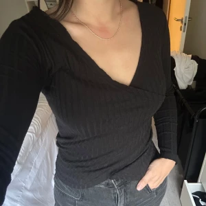 Svart ribbad omlottopp - Säljer en snygg svart ribbad omlottopp i storlek S. Sitter så snyggt mot kroppen och passar både fest och vardag beroende på hur man matchar den. Materialet är mjukt och stretchigt. Lite ytludd därav billigt pris 🖤