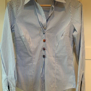 Boss skjorta/blus randig vit/blå med fina detaljer - Boss (Hugo Boss) otroligt fin unik skjorta i härlig stretchig kvalite med fina detaljer. Skicket är väldigt bra. 