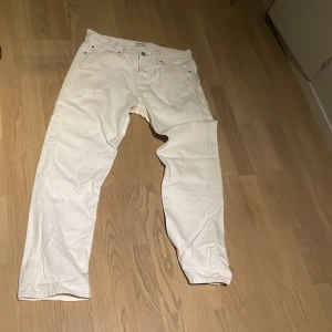 Vita byxor Jack & Jones  - Säljer ett par vita byxor i modellen Relaxed/Chris. De har en avslappnad passform och är perfekta för en casual look. Byxorna har en klassisk design med knappar och dragkedja framtill. Perfekta för både vardag och fest!