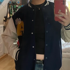 Blå Collegejacka - En blå college-jacka från HM i tjockt material. Bara använd en gång så är i mycket bra skick. Storlek XS men väldigt oversize, så beroende på hur man vill att den ska passa kan det också vara S/M :) 