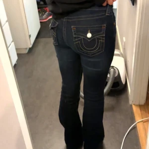 Mörkblå jeans från True Religion - Snygga mörkblå jeans från True Religion med bootcut-stil. De har dekorativa sömmar och knappar på bakfickorna. Storlek 28 nypris 1299kr. Beccamodellen. 