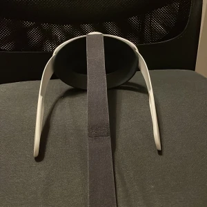 Vit VR-huvudrem - Säljer en vit VR-huvudrem med justerbart band. Remmen är designad för att ge en bekväm passform och stöd under användning av VR-headset. Perfekt för att förbättra din VR-upplevelse.
