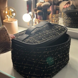 Svart och guld necessär - Säljer en jättefin necessär som är jättefin! Får plats mycket i den och har ett fack! En av dragkedjorna har gått sönder men funkar fortfarande jättebra