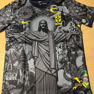 Svart och grå Brasilien fotbollströja från Nike - Unik svart och grå fotbollströja från Nike med Brasilien-tema. Tröjan har ett detaljerat mönster med Kristusstatyn och andra ikoner. Den har korta ärmar och Brasilien-emblem på bröstet. Perfekt för fotbollsfans som vill sticka ut!