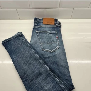 Blå jeans från Replay(slitningar) - Snygga blå jeans från Replay med en klassisk femficksdesign. De har slitningar för en trendig look och en bekväm passform. Perfekta för en riktigt grich/laidback stil😎. Byxorna är väldigt bra skick nästan som nya eftersom jag bara använt dom en gång! 
