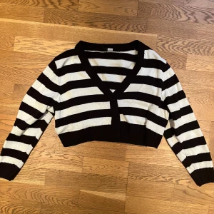 Svartvit randig croppad tröja - Säljer en svartvit randig croppad tröja med v-ringning. Tröjan har långa ärmar och är perfekt för en trendig look. Passar bra till både jeans och kjol.